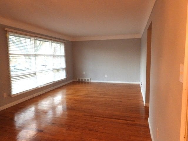 empty room with ornamental molding and hardwood / wood-style floors