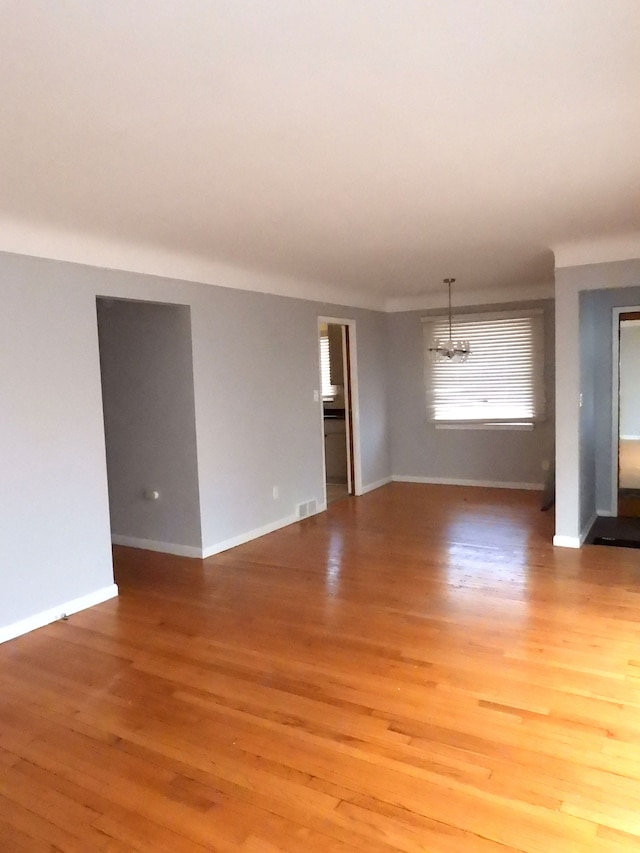 empty room featuring hardwood / wood-style floors and a notable chandelier