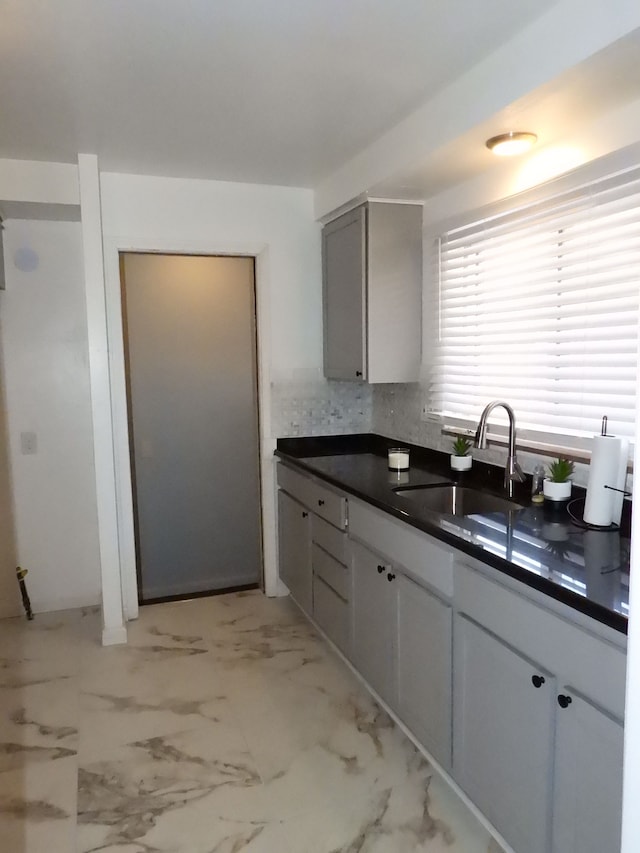 kitchen with gray cabinets, tasteful backsplash, and sink