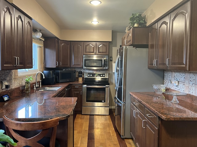 kitchen with stainless steel appliances, sink, dark brown cabinetry, and light wood-type flooring