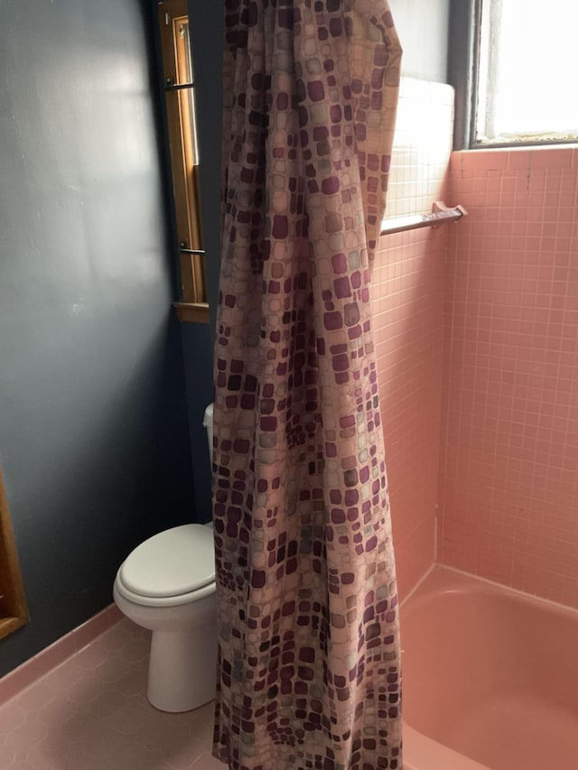 bathroom with tile patterned flooring, shower / tub combo, and toilet