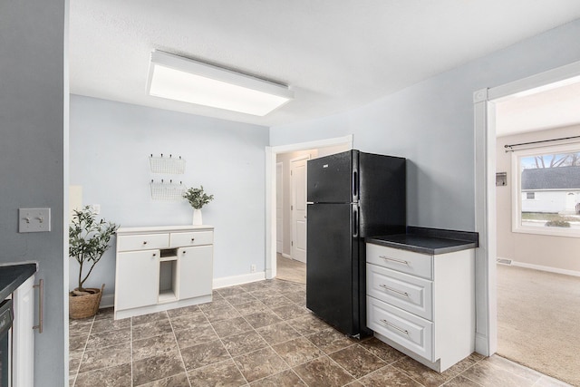 kitchen featuring black refrigerator, dark carpet, and white cabinets