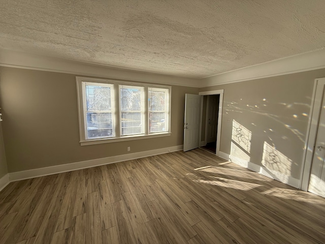 unfurnished room featuring a textured ceiling, baseboards, and wood finished floors