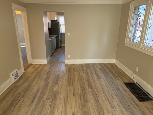 unfurnished room with crown molding and light wood-type flooring