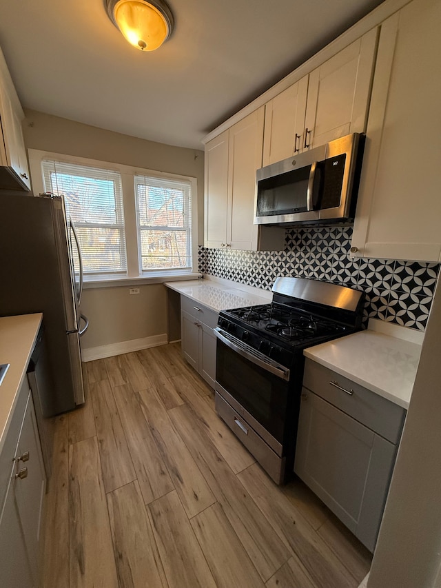 kitchen featuring tasteful backsplash, appliances with stainless steel finishes, light hardwood / wood-style flooring, and white cabinets