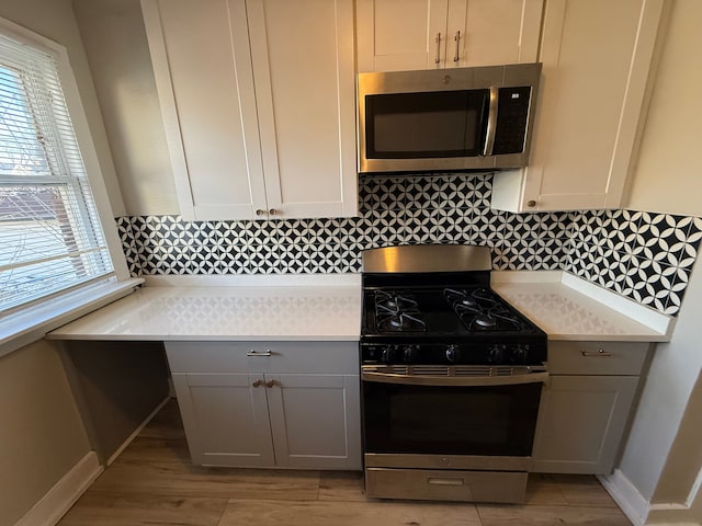 kitchen featuring stainless steel appliances, light hardwood / wood-style floors, and decorative backsplash