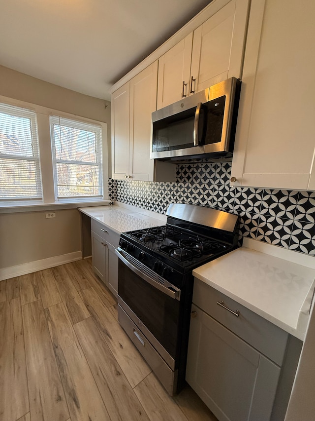 kitchen with tasteful backsplash, white cabinetry, appliances with stainless steel finishes, and gray cabinetry