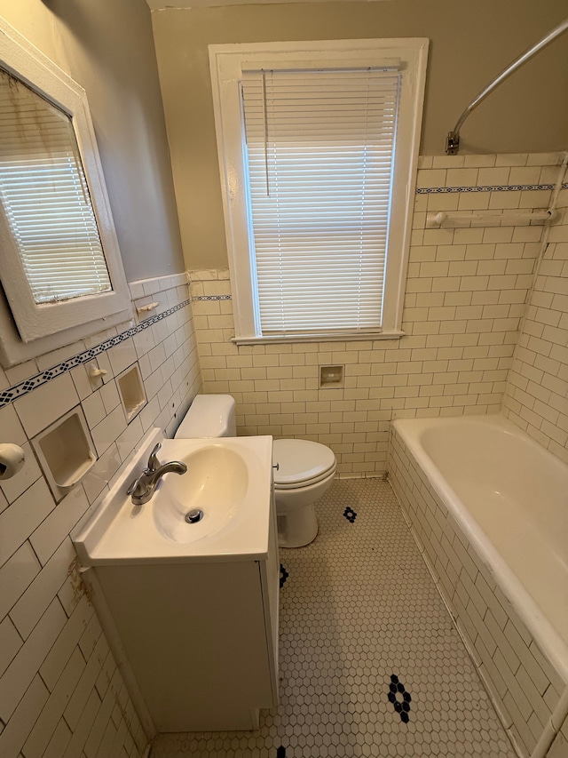 bathroom featuring vanity, tile patterned flooring, tile walls, toilet, and tiled shower / bath