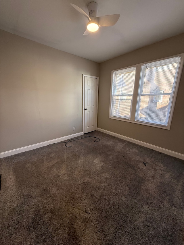 unfurnished room with dark carpet and ceiling fan