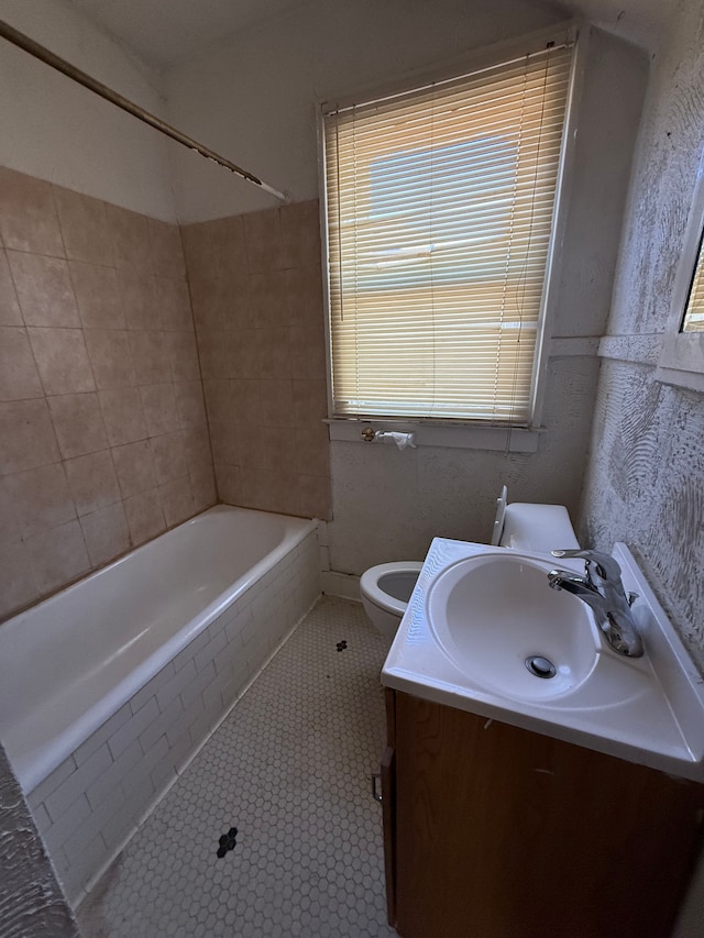 full bathroom featuring tiled shower / bath, vanity, toilet, and tile patterned flooring