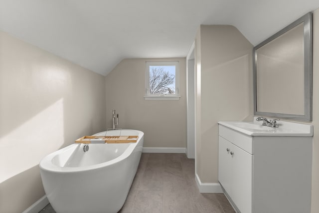 bathroom with lofted ceiling, a tub to relax in, and vanity