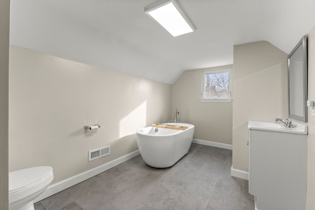 bathroom featuring vaulted ceiling, a bathing tub, vanity, and toilet