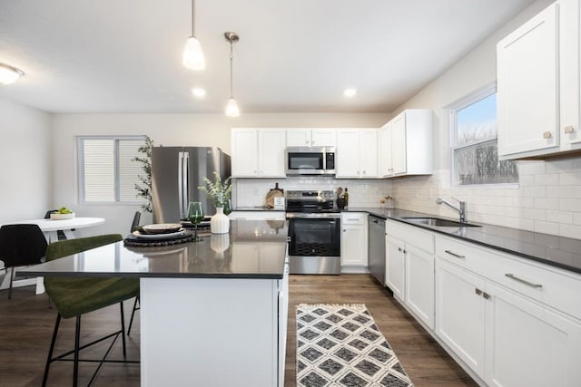 kitchen with appliances with stainless steel finishes, decorative light fixtures, sink, a kitchen bar, and a center island