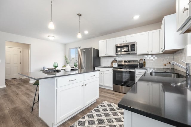 kitchen with stainless steel appliances, sink, a kitchen island, and white cabinets