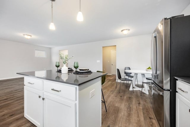 kitchen with stainless steel refrigerator, decorative light fixtures, a kitchen island, and white cabinets