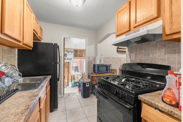 kitchen with light tile patterned flooring, light stone countertops, black gas range, and backsplash