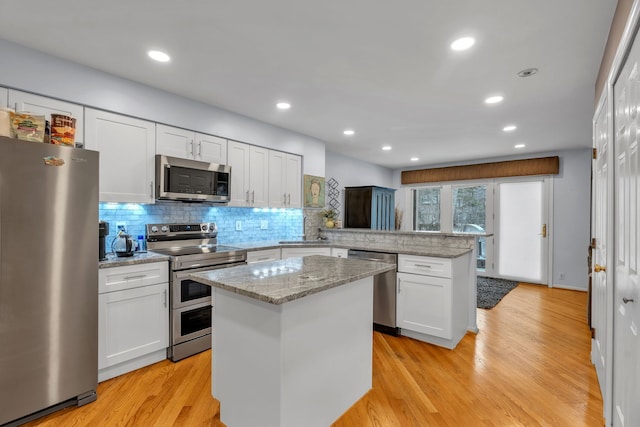 kitchen with white cabinetry, stainless steel appliances, a center island, and kitchen peninsula