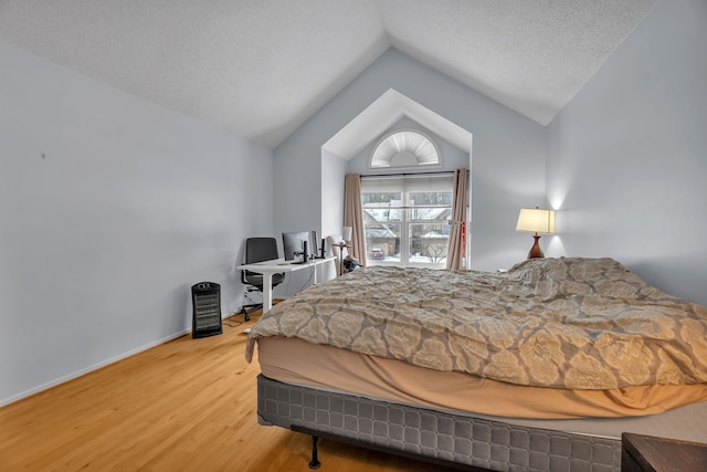 bedroom with hardwood / wood-style flooring, lofted ceiling, and a textured ceiling