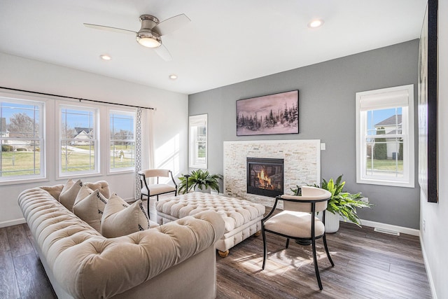 living room with dark hardwood / wood-style flooring, ceiling fan, and a fireplace