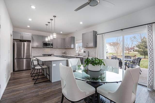 dining area featuring sink, ceiling fan with notable chandelier, and dark hardwood / wood-style floors