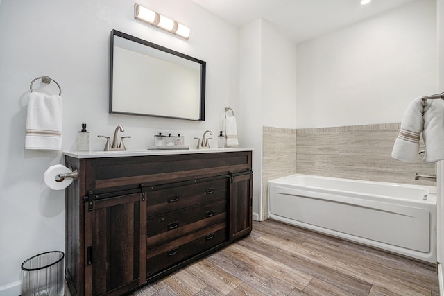 bathroom featuring vanity, a bath, and wood-type flooring