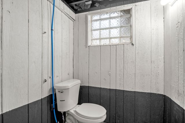 bathroom with toilet and wood walls