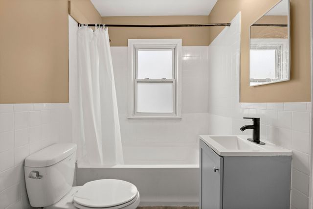 full bathroom featuring tile walls, vanity, shower / bath combination with curtain, and toilet