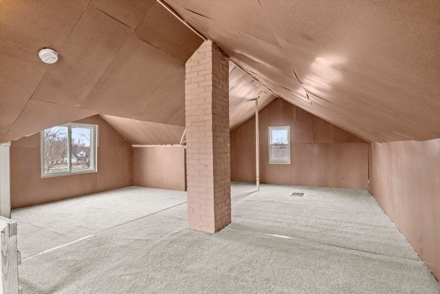 additional living space with ornate columns, vaulted ceiling, and light carpet