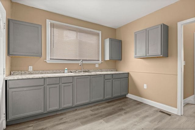 kitchen with light wood-type flooring, sink, and gray cabinetry