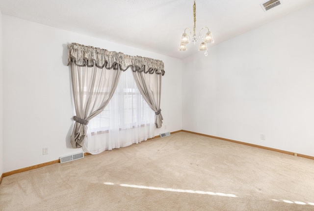 empty room featuring a chandelier and carpet flooring