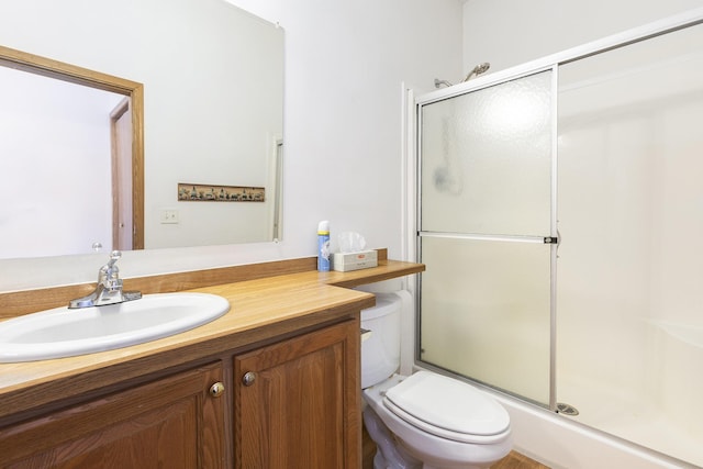 bathroom featuring vanity, an enclosed shower, and toilet