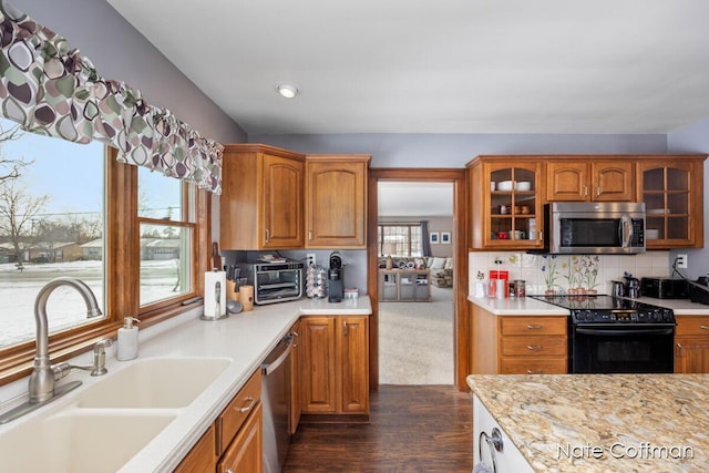 kitchen with sink, appliances with stainless steel finishes, dark hardwood / wood-style floors, tasteful backsplash, and light stone countertops