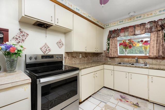 kitchen with sink, light tile patterned floors, tasteful backsplash, stainless steel electric range oven, and cream cabinetry