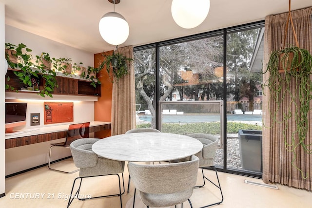 dining room with a wealth of natural light, built in desk, and a wall of windows