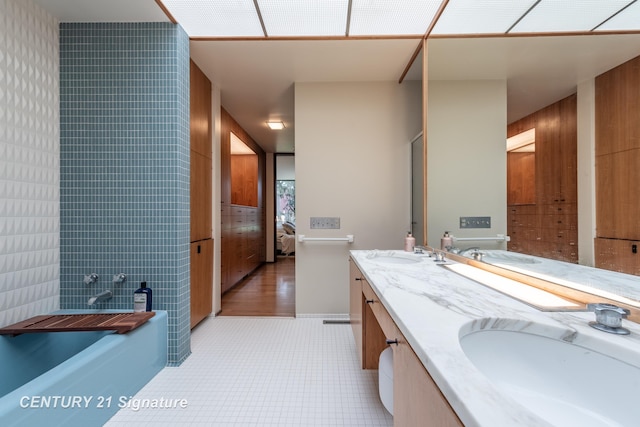 bathroom with vanity, a bath, tile patterned flooring, and tile walls