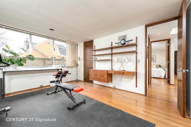 exercise room featuring hardwood / wood-style floors and built in desk