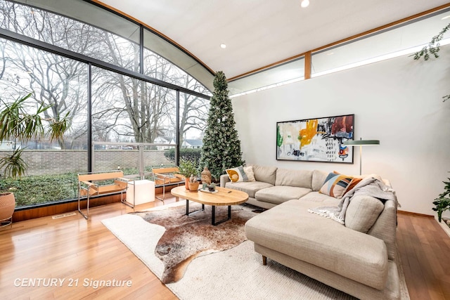 living room featuring hardwood / wood-style flooring, a wall of windows, and a high ceiling