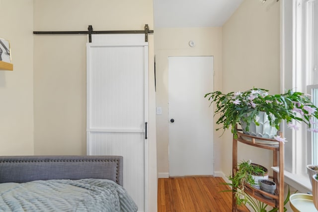 bedroom featuring a barn door and light hardwood / wood-style flooring