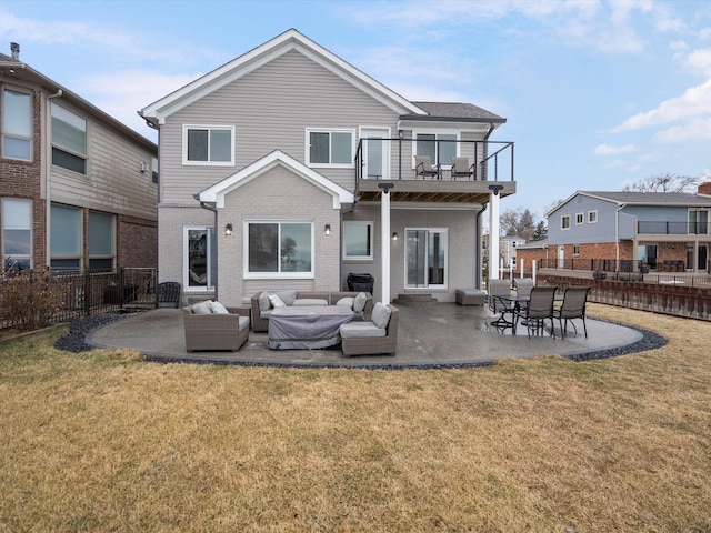 rear view of house featuring a balcony, a patio area, and a lawn