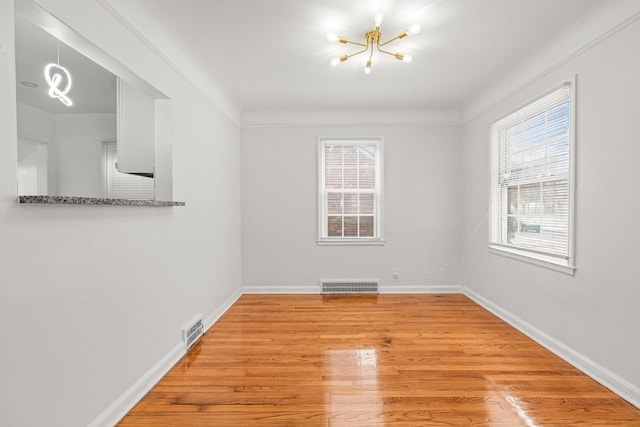 unfurnished room with an inviting chandelier, light hardwood / wood-style flooring, and a healthy amount of sunlight