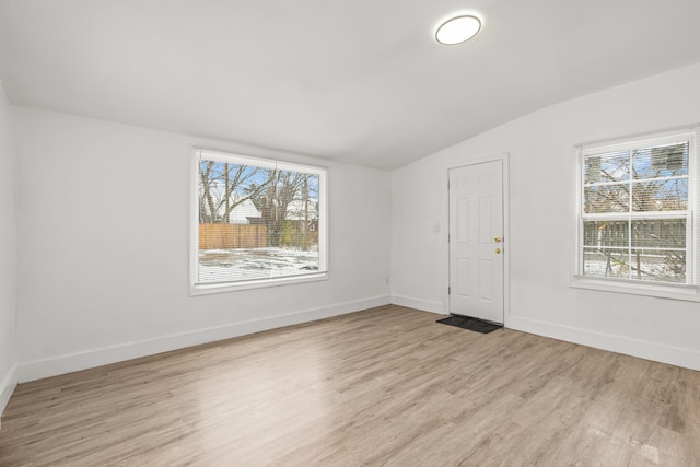 spare room with lofted ceiling and light wood-type flooring