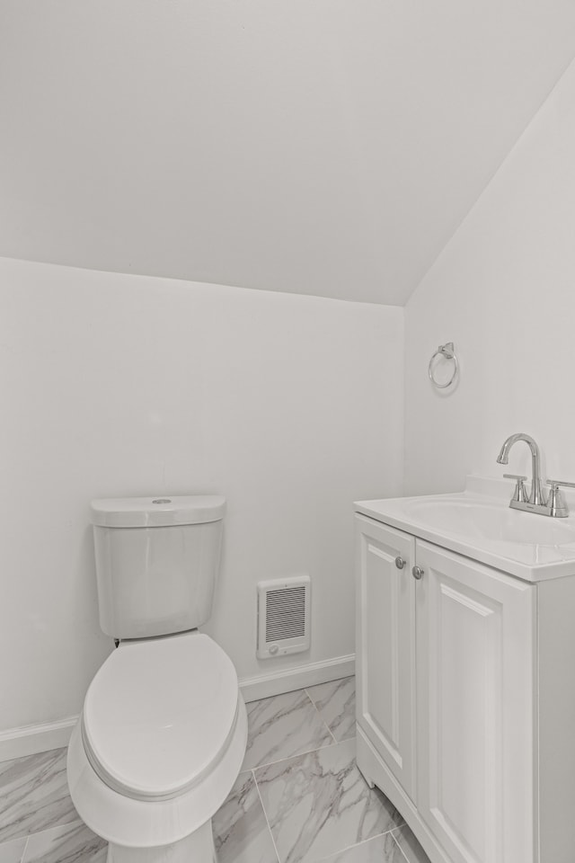 bathroom featuring vanity, lofted ceiling, and toilet