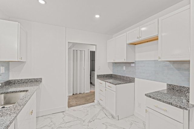 kitchen featuring sink, decorative backsplash, white cabinets, and stone counters