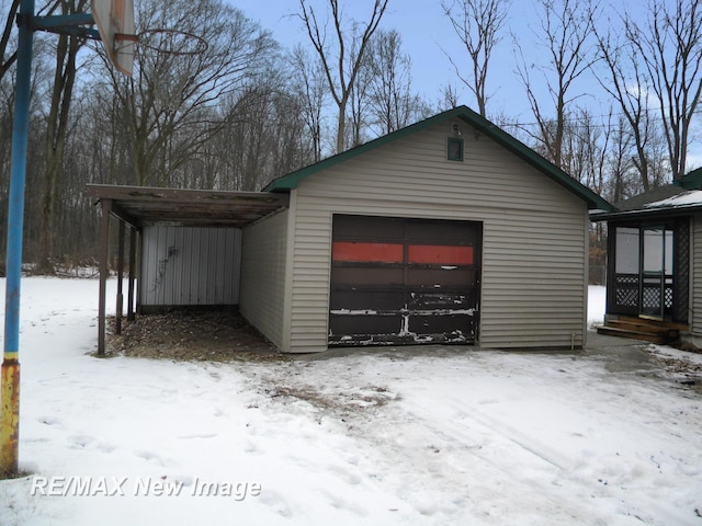 snow covered garage featuring a carport