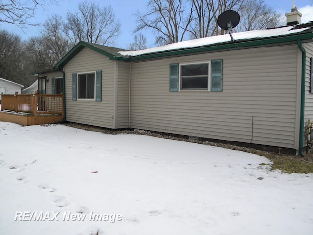 snow covered house featuring a wooden deck