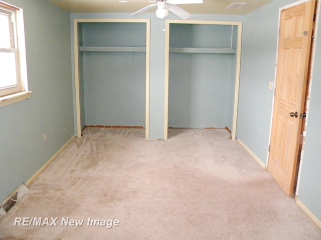 unfurnished bedroom with multiple closets and light carpet