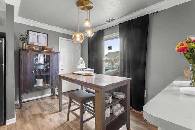 dining area featuring hardwood / wood-style floors, ornamental molding, and a textured ceiling