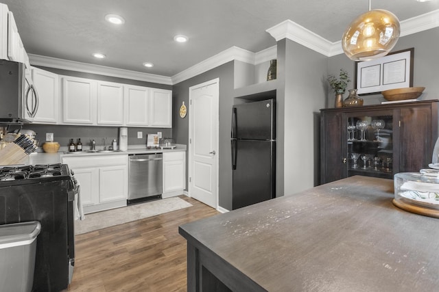 kitchen with pendant lighting, dark wood-type flooring, ornamental molding, black appliances, and white cabinets