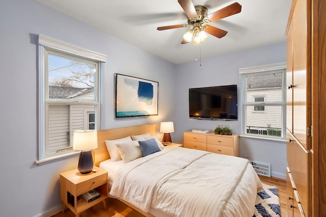 bedroom featuring multiple windows, ceiling fan, and light wood-type flooring