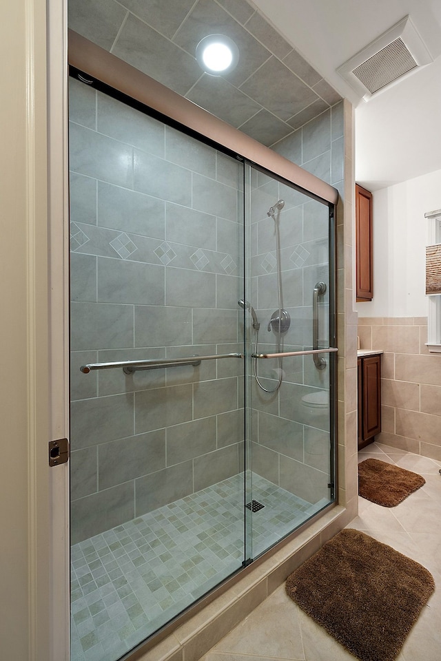 bathroom featuring a shower with door, tile walls, and tile patterned floors